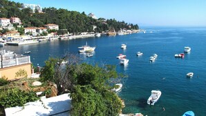 A coastal town with boats docked along the waterfront, buildings on the hillside, and a clear blue sky. - Beautiful apartment for 4 guests with A/C, WIFI, TV and balcony (Labin)