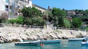 A coastal building with balconies, a stone wall, and boats docked nearby. - Beautiful apartment for 4 guests with A/C, WIFI, TV and balcony (Labin)