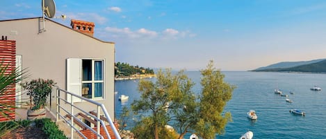 A coastal building with a balcony overlooking a marina with several boats.