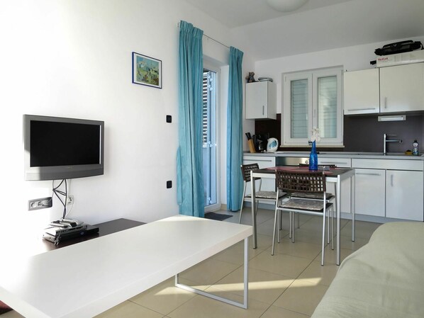 Habitación compacta con televisión, mesa de comedor, zona de cocina y cama.