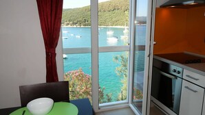 A kitchen with an oven and a view of a bay with boats. - Nice apartment for 2 guests with A/C, WIFI, TV and balcony (Labin)