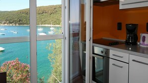 A kitchen with a view of boats on a turquoise sea, a coffee maker, and an oven. - Nice apartment for 2 guests with A/C, WIFI, TV and balcony (Labin)