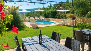 Un jardin avec une piscine, des meubles d’extérieur et des guirlandes lumineuses.