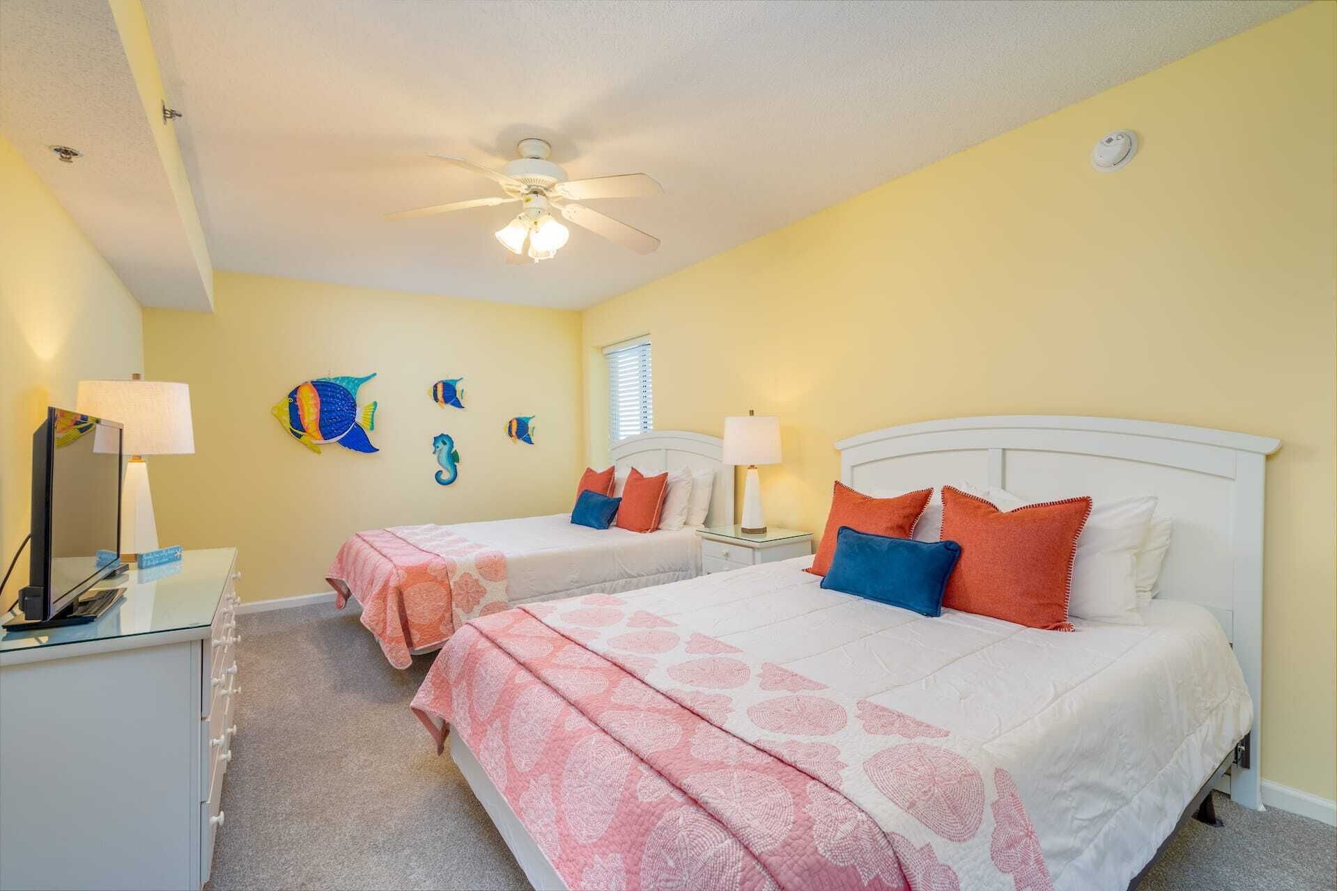 A bedroom with two beds, a ceiling fan, and a wall-mounted fish decoration.