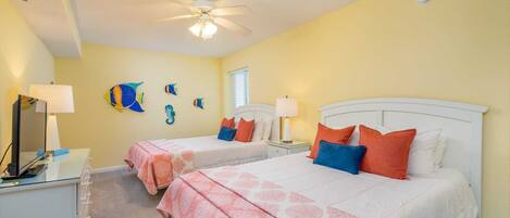 A bedroom with two beds, a ceiling fan, and a wall-mounted fish decoration.