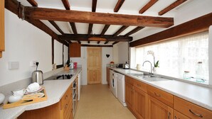 A kitchen with wooden beams, a washing machine, and a window with curtains. - Yew Tree Farm Cottage.. (Congleton)