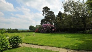 A well-maintained lawn with a stone pathway, a birdbath, and a variety of flowering plants. - Yew Tree Farm Cottage.. (Congleton)