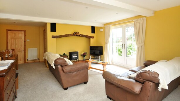 A living room with two brown leather sofas, a wooden coffee table, a television, and a fireplace. - Yew Tree Farm Cottage.. (Congleton)