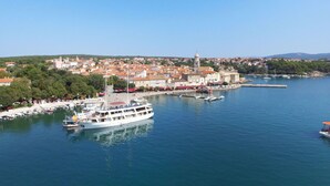 A coastal town with a prominent white boat docked at the harbor, surrounded by buildings and a clear sky. - Nice apartment for 4 guests with WIFI, A/C, TV, balcony and pets allowed (Novi Vinodolski)