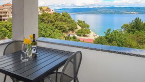 A balcony with a table and chairs overlooking a lake and mountains.