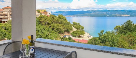 A balcony with a table and chairs overlooking a lake and mountains.