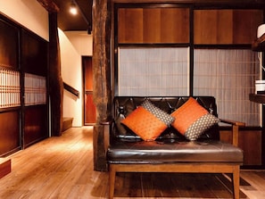 Traditional-style interior with a wooden floor and a black leather sofa, featuring a sliding shoji screen door.