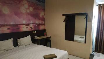 Una habitación de hotel con una cama, un escritorio, un espejo y una repisa en la pared.