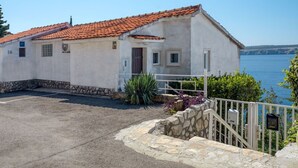 Un edificio costero con techo de tejas, base de piedra y vista al mar.
