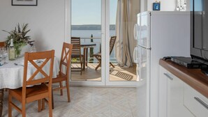 Una habitación con una mesa de comedor preparada para dos personas, un refrigerador y un televisor sobre una encimera de madera.
