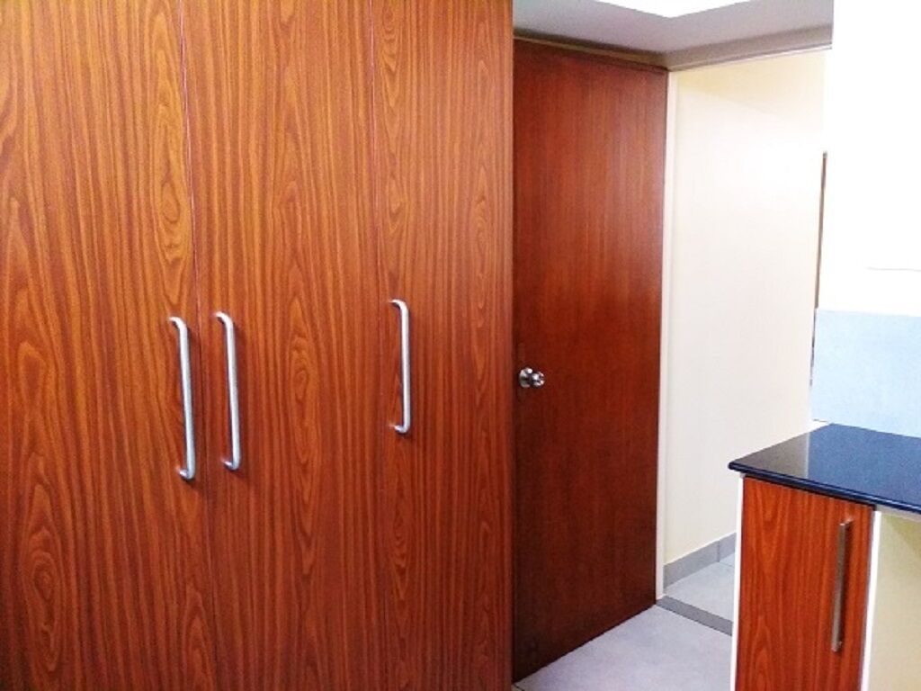 A wooden wardrobe with two handles and a door.