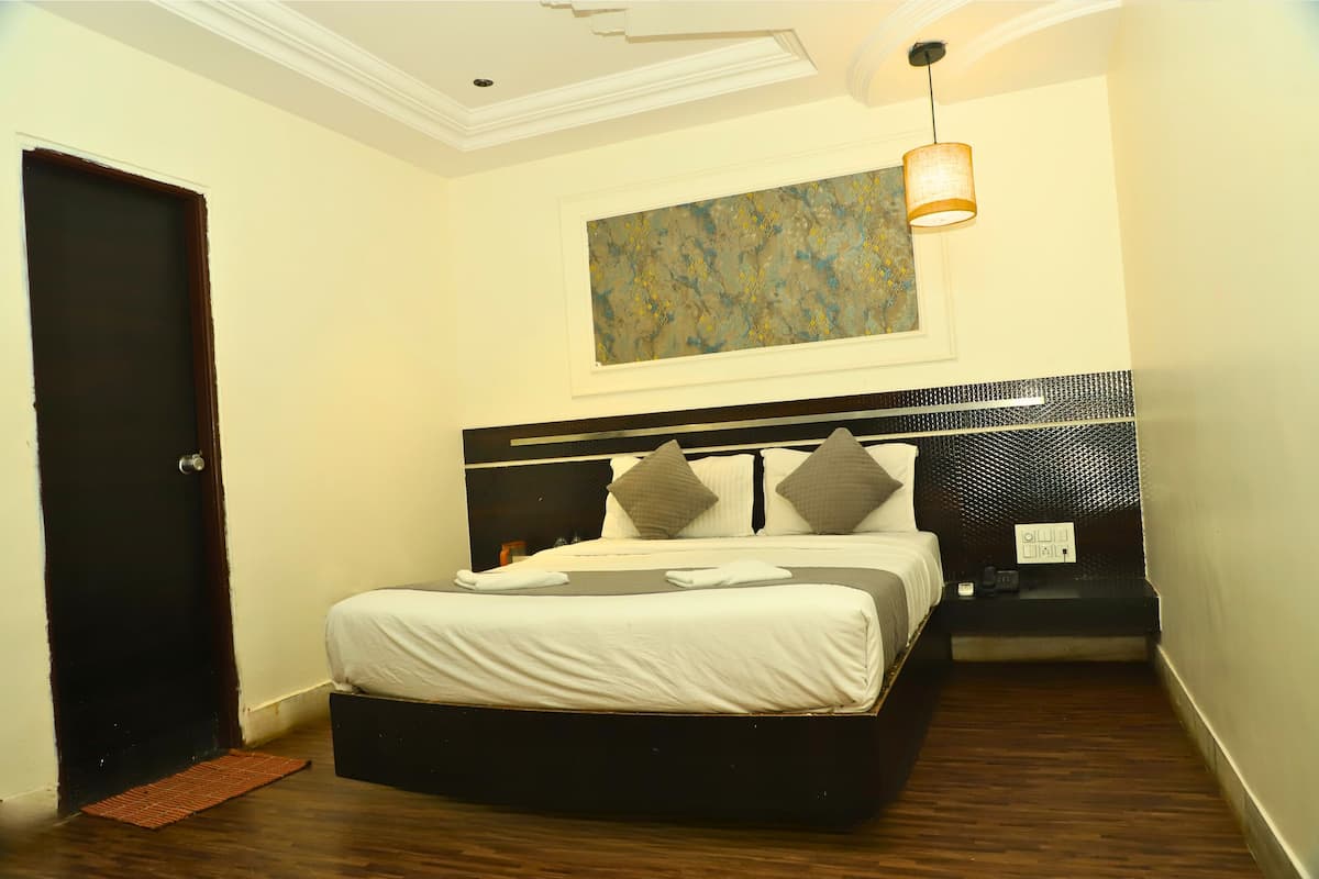 A bedroom with a bed, a nightstand, a lamp, and a painting on the wall.