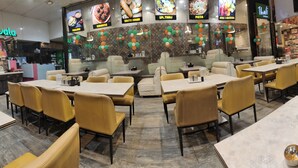 A restaurant with multiple tables and chairs, a counter with a menu, and a wall decorated with colorful balloons. - Hotel Shirdi Park Inn 80 Meters From Sai Samadhi Temple (Rahata)