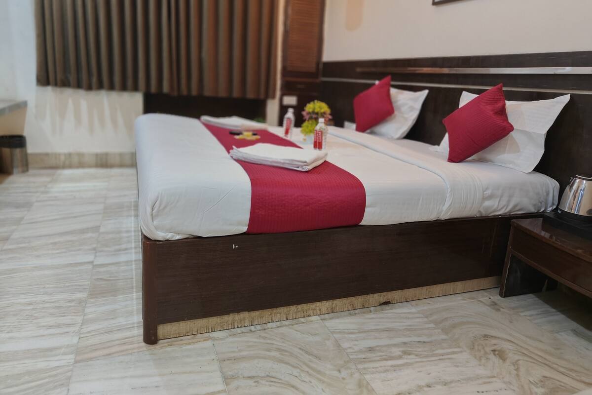 A hotel room with a large bed, two pillows, a bedside table, and a nightstand.