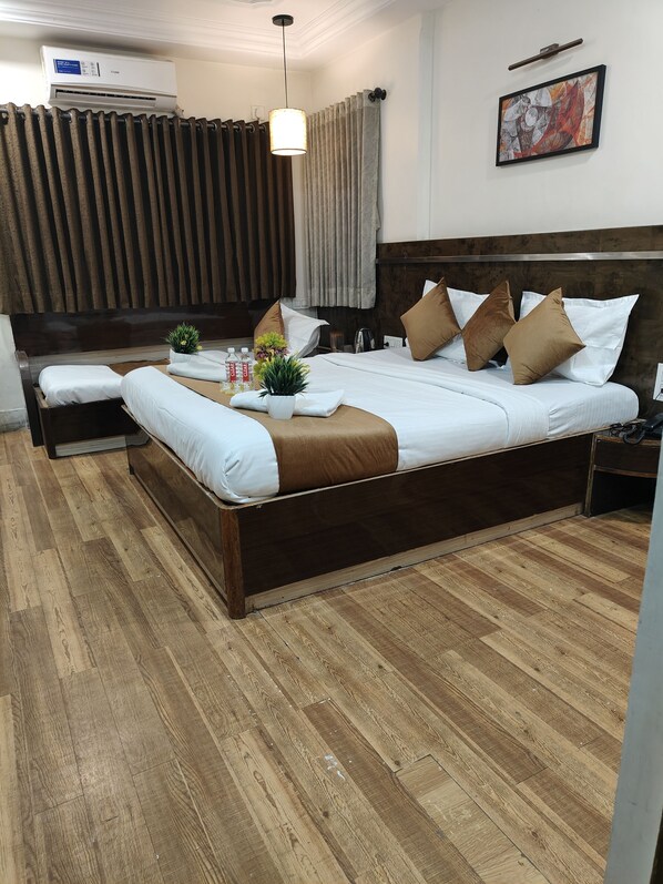 A modern hotel room with a wooden bed, a bedside table, a nightstand, a potted plant, and a ceiling fan.