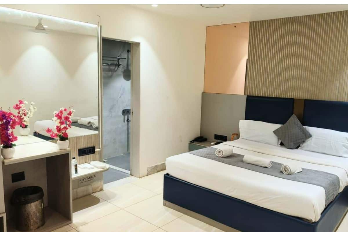 A modern hotel room with a bed, bedside table, and a shower area.