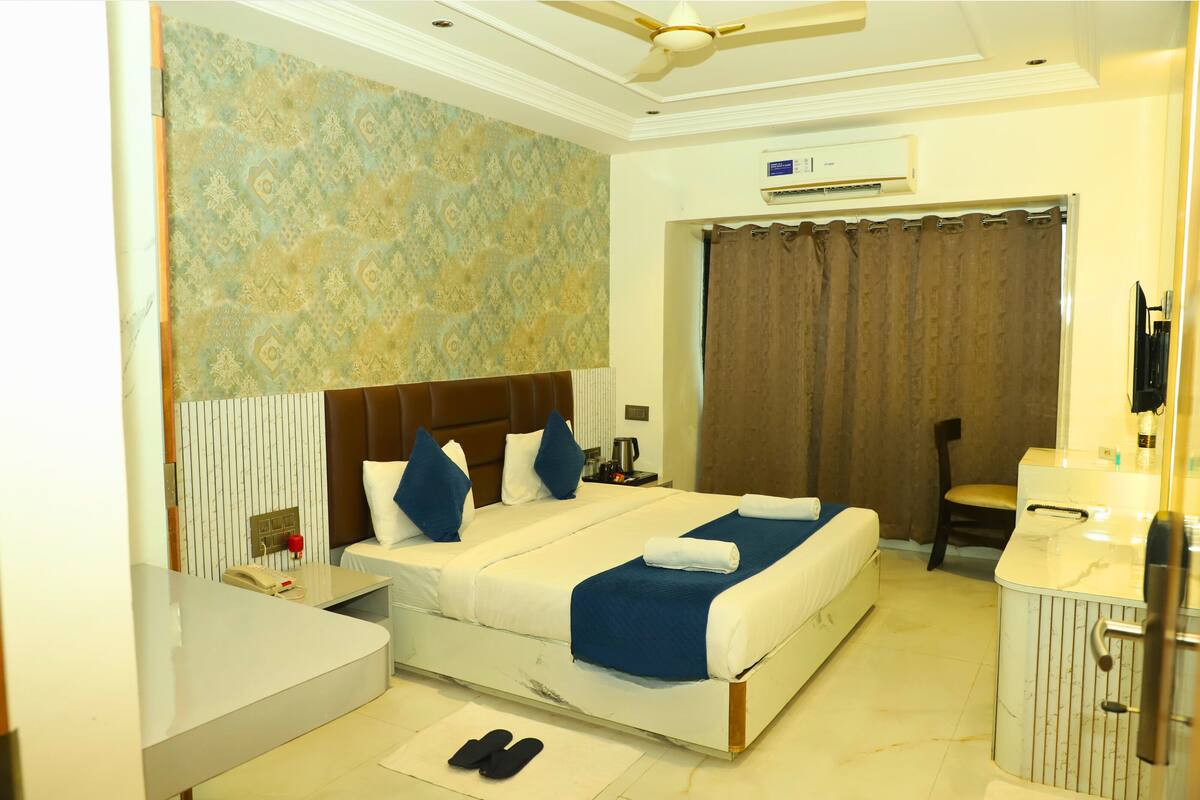 A hotel room with a bed, a desk, a chair, and a bathroom.