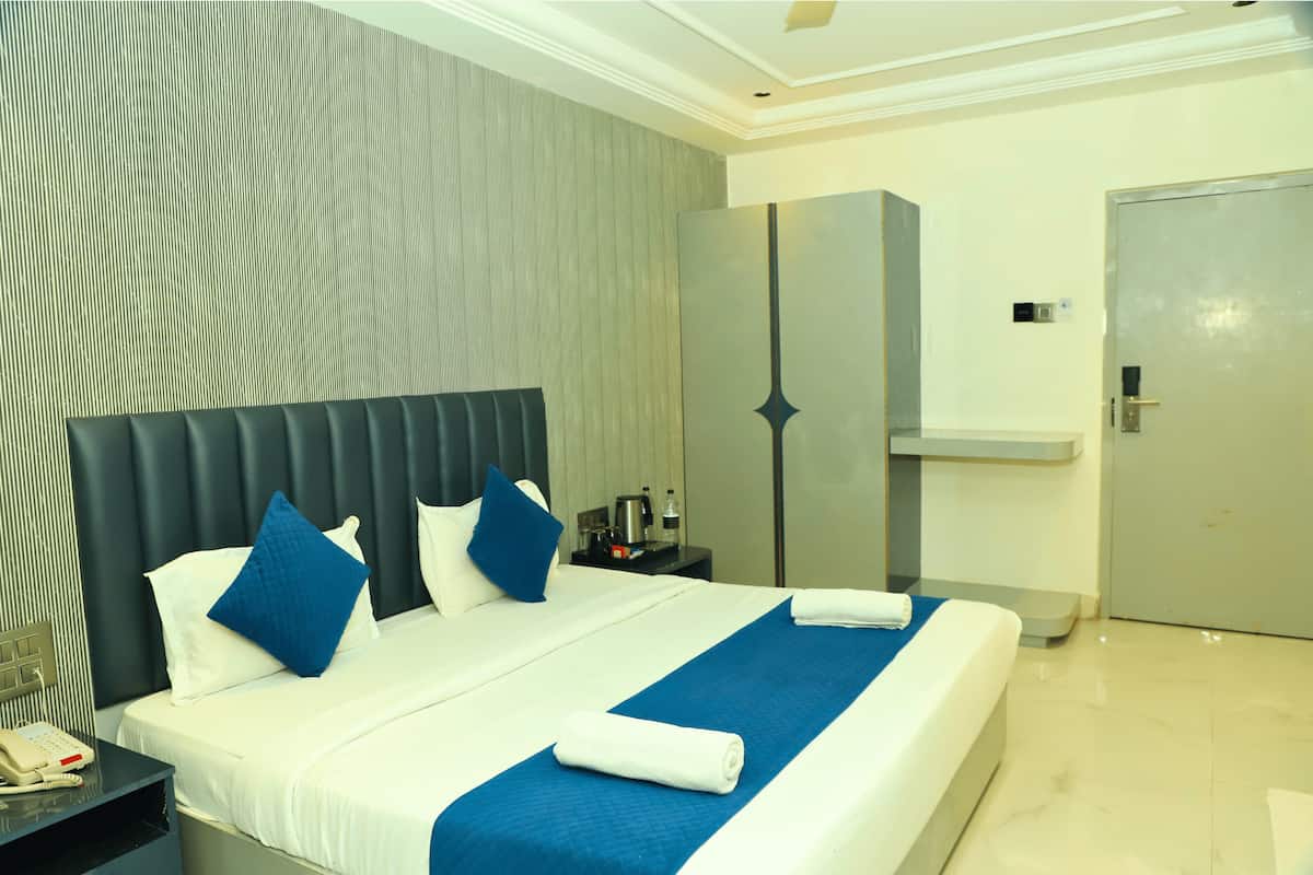 A hotel room with a large bed, a nightstand, a wardrobe, and a door.