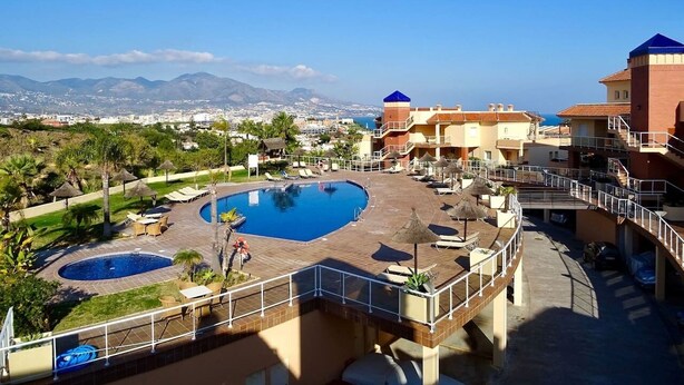 A resort with a large pool, multiple buildings, and a view of the mountains.