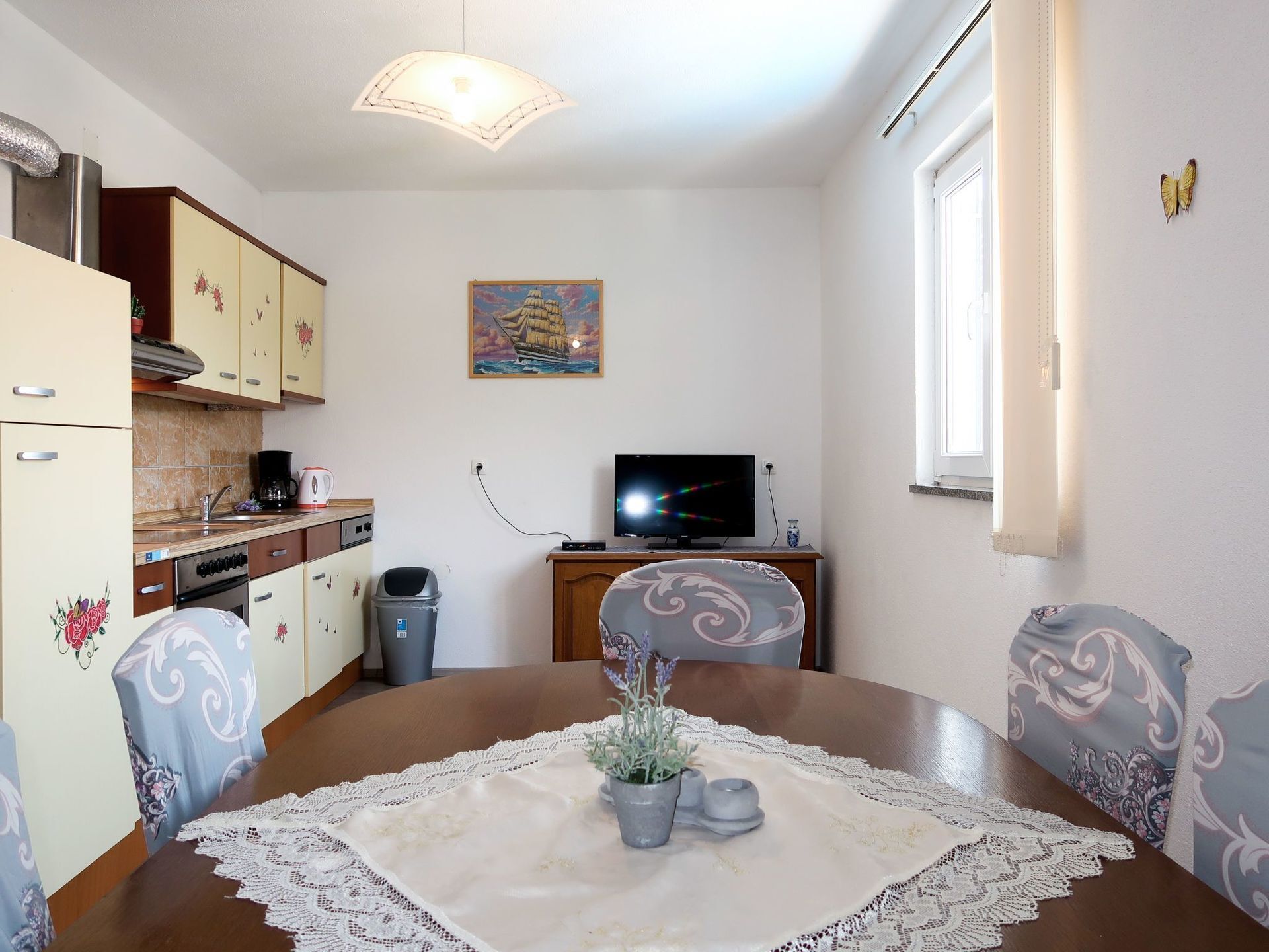 A compact living space with a dining table, chairs, a television, and a kitchen area.