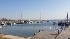 Ein Yachthafen mit mehreren angedockten Booten, einer Holzsteganlage und blauem Himmel.