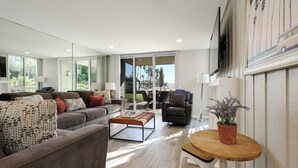 A modern living room with a grey sofa, a wooden coffee table, and a potted plant. - Your Own Slice of Paradise! Patio & Grass Just Steps from the Sand! (Oceanside)