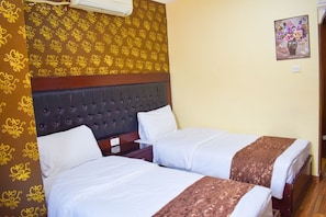 A hotel room with two beds, a dark headboard, and patterned wallpaper.