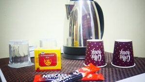 Un tavolo con una scatola di tè Alghazaleen, due bustine di caffè Nescafe, due tazze a pois e un bollitore.