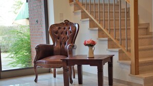 Une chaise et une table en bois se trouvent dans une pièce qui comprend un escalier et une fenêtre.