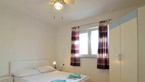 A bedroom with a bed, nightstand, wardrobe, and curtains. - Cosy apartment for 5 people with A/C, WIFI, TV, balcony and pets allowed (Vodice)