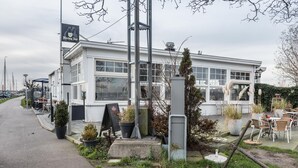 A white building with large windows, outdoor seating, and potted plants. - Meeuwen Manor - A treasure near Amsterdam (Edam)