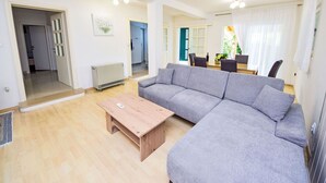Una sala de estar amplia con un sofá gris, una mesa de centro de madera y un comedor con una mesa y sillas.