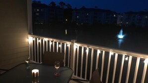 Un balcone con tavolo e sedie, una candela e luci a stringa.