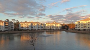 Un hotel sul lungolago con diversi edifici, una fontana centrale e un lago calmo che riflette il cielo.
