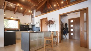 Une cuisine moderne avec un îlot central, des chaises en bois et une vue sur l’extérieur.