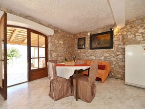 Enjoy meals in this inviting dining area with a table for two, a refrigerator, and a large glass door leading to an outdoor space.