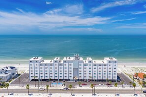Ein mehrstöckiges Hotel mit flachem Dach, gelegen neben einem Strand mit freiem Blick auf den Ozean.