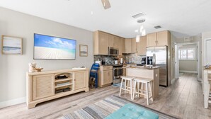 Una cocina moderna con armarios de madera, un refrigerador de acero inoxidable y una isla grande con taburetes.