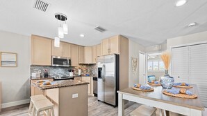 Una cocina moderna con armarios de madera, electrodomésticos de acero inoxidable y una isla central con taburetes.