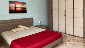 A bedroom with a bed, a nightstand, a wardrobe, and a wall-mounted picture.