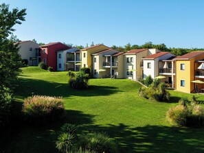 Une rangée d’immeubles à étages avec des balcons, une pelouse bien entretenue et des espaces de détente en plein air.
