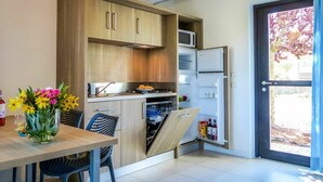 Una cocina moderna con armarios de madera, microondas integrado y refrigerador. Hay una mesa de comedor con sillas y un florero con flores.