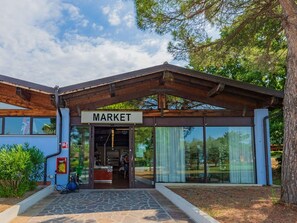 A market building with a sign, a covered entrance, and a view of the interior through large glass windows.