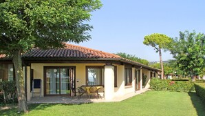 Ein zweistöckiges Haus mit Ziegeldach, einer überdachten Veranda mit Stühlen und einem gepflegten Rasen.