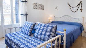 A room with a bed, a sofa, a lamp, and a wall with pictures and a cross. - S187 - Sirolo, delightful sky-earth house in the alleys (Sirolo)